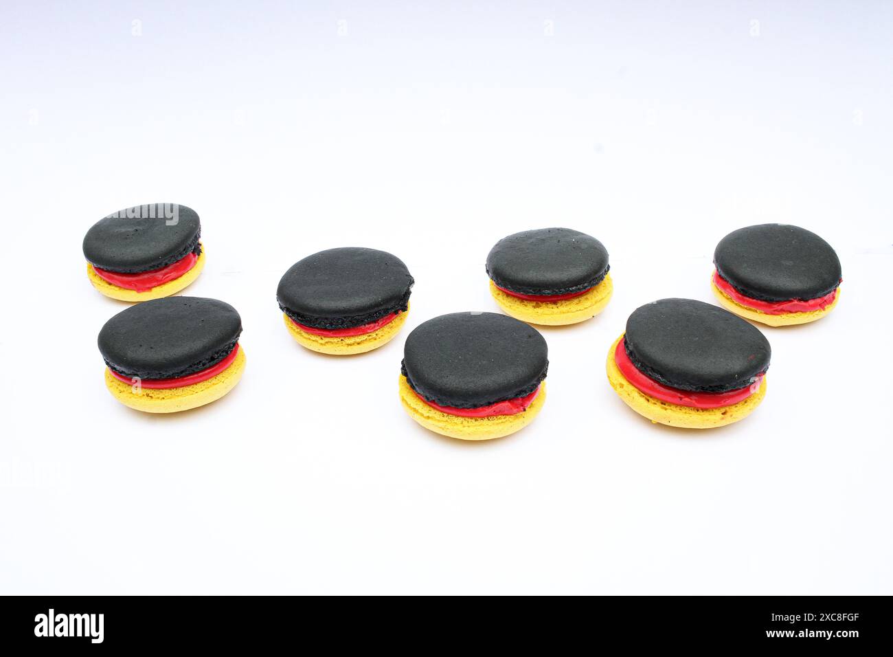Macroons in den deutschen Nationalfarben Gelb, Rot und Schwarz auf weißem Hintergrund mit Kopierraum, konzeptionelles Foto als Unterstützung für deutsche Sportmannschaften EM Stockfoto