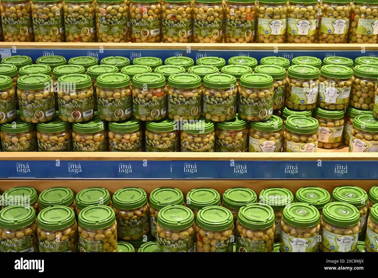 Reihen grüner Oliven in Gläsern zum Verkauf im Supermarkt Stockfoto