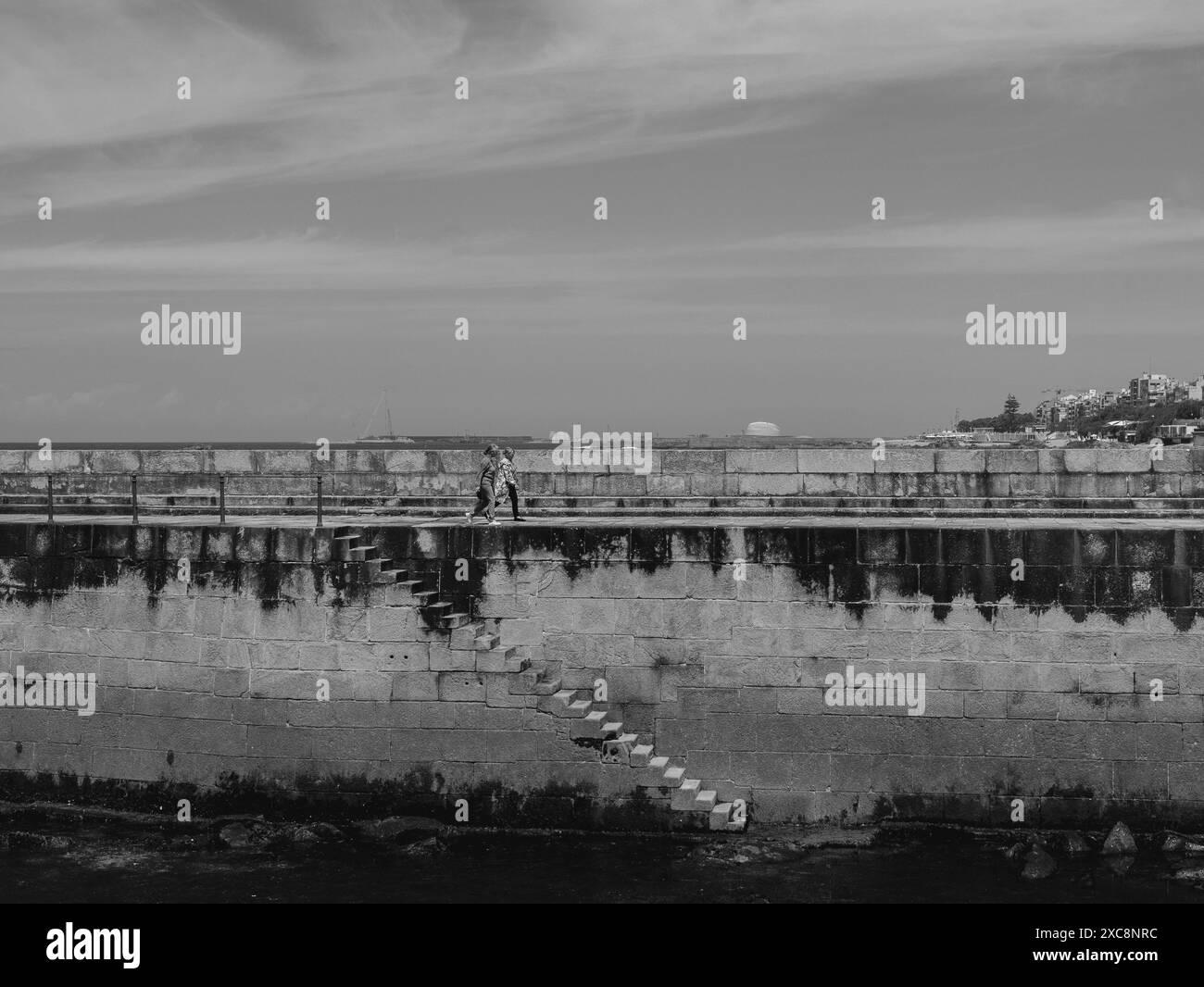 Schwarz-weiß tritt vom Felgueiras Quay in das Wasser ein, der zum Felgueiras Lighthouse in Foz do Douro in der Nähe von Porto, Portugal.27.05.2024 Stockfoto