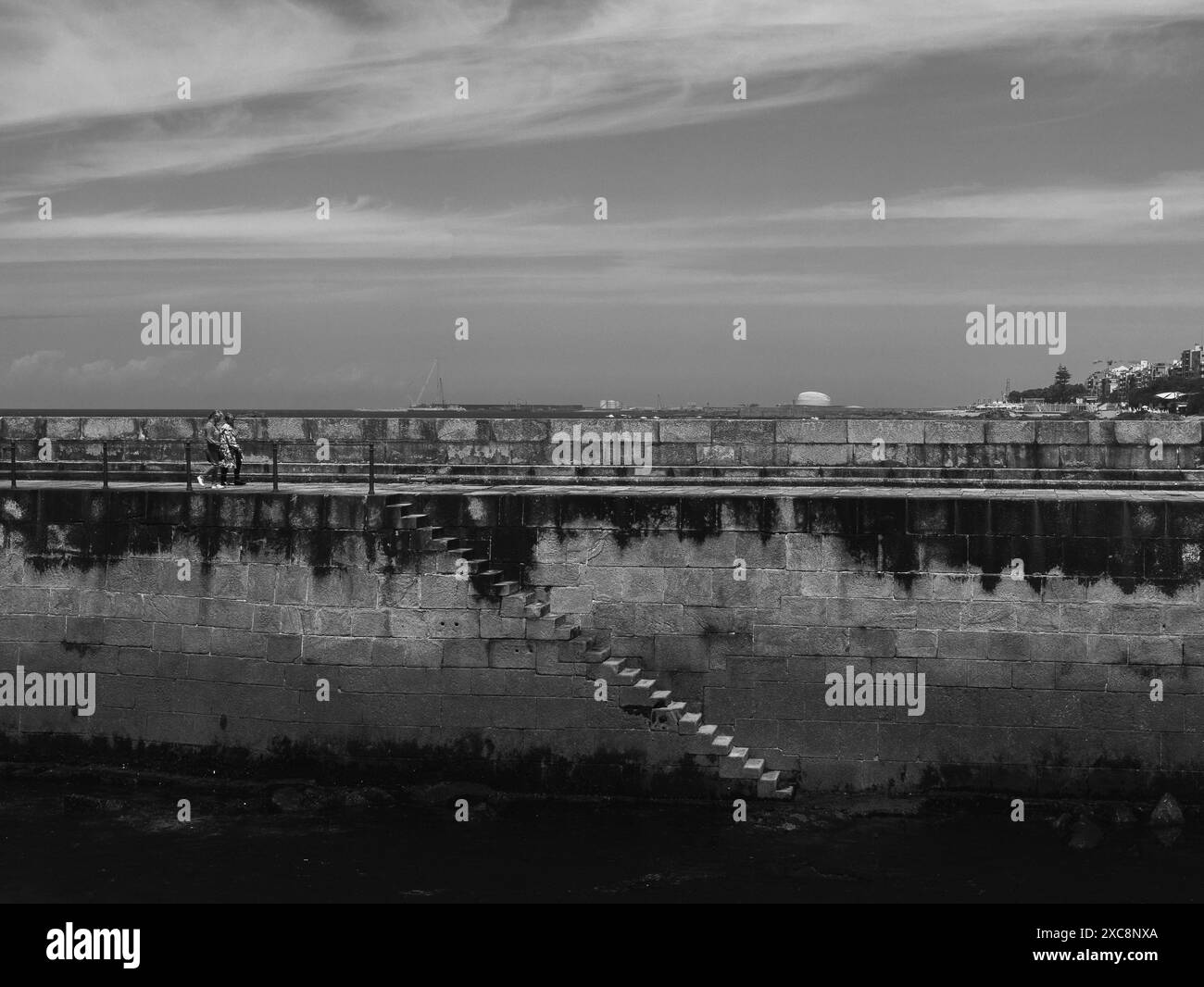 Schwarz-weiß tritt vom Felgueiras Quay in das Wasser ein, der zum Felgueiras Lighthouse in Foz do Douro in der Nähe von Porto, Portugal.27.05.2024 Stockfoto