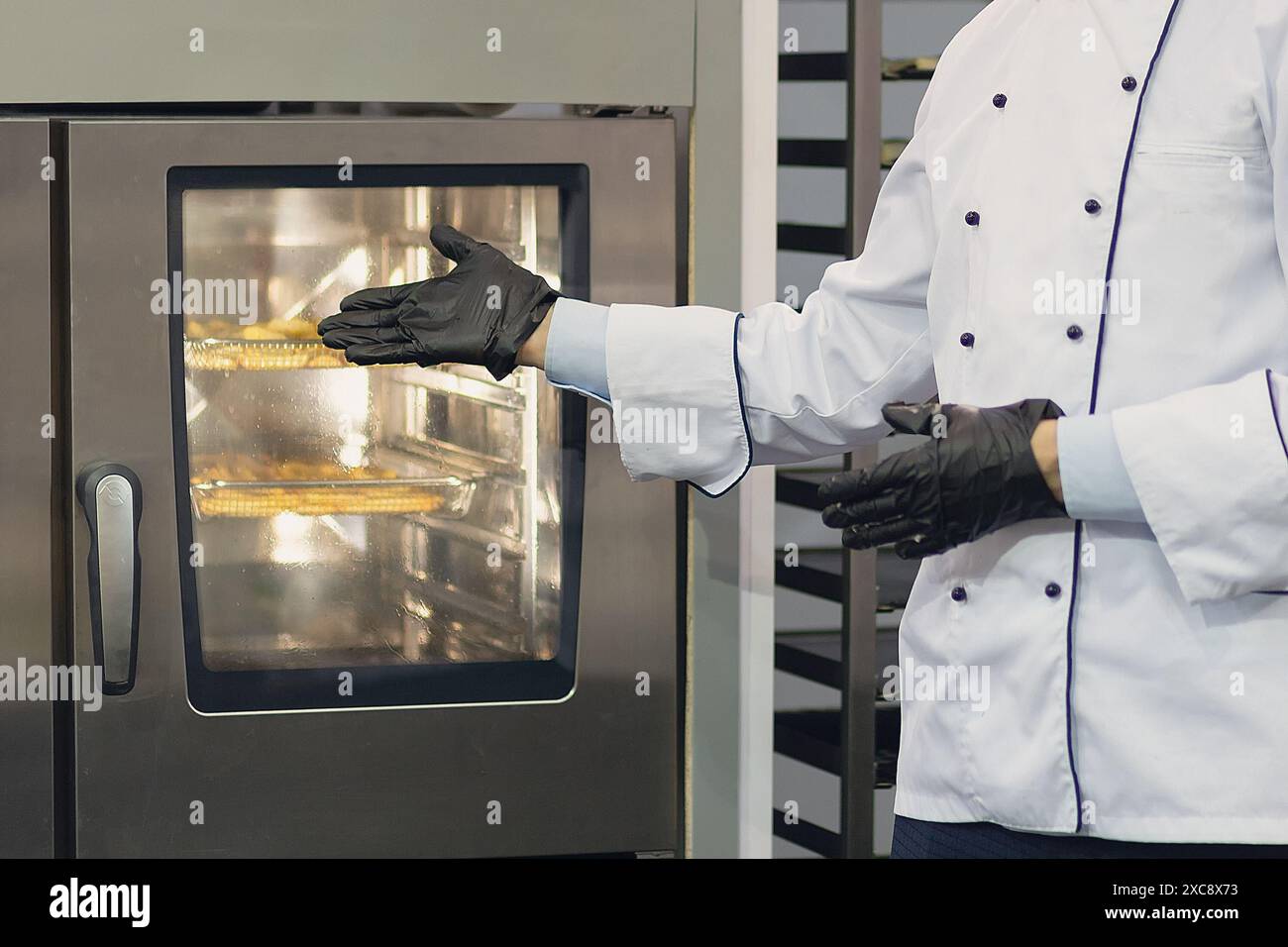 In der Bäckerei: bäcker in der Nähe eines elektrischen Ofens. Lebensmittelindustrie Stockfoto
