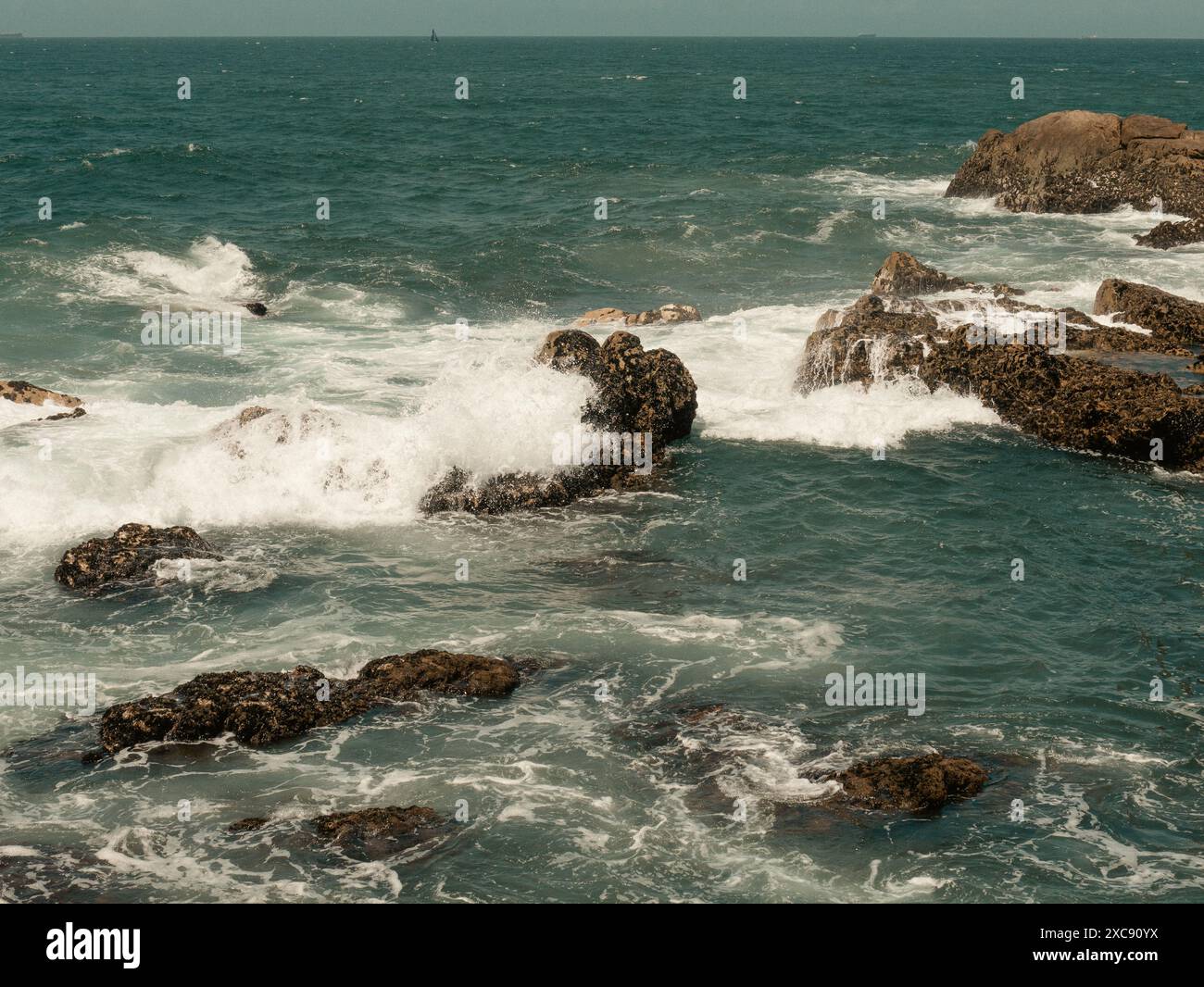 Filmische Nahaufnahme, wie die Wellen des Atlantiks auf den großen felsigen Steinfelsen portugals brechen Stockfoto