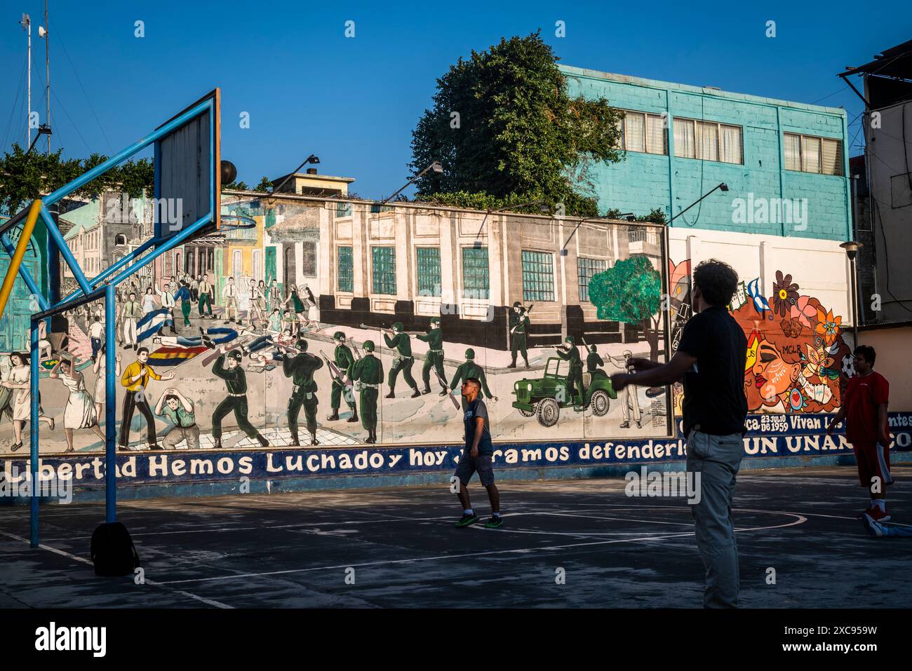 Sportspielplatz mit großem Wandbild, das Szenen aus der nicaraguanischen Geschichte, Leon, Nicaragua zeigt Stockfoto