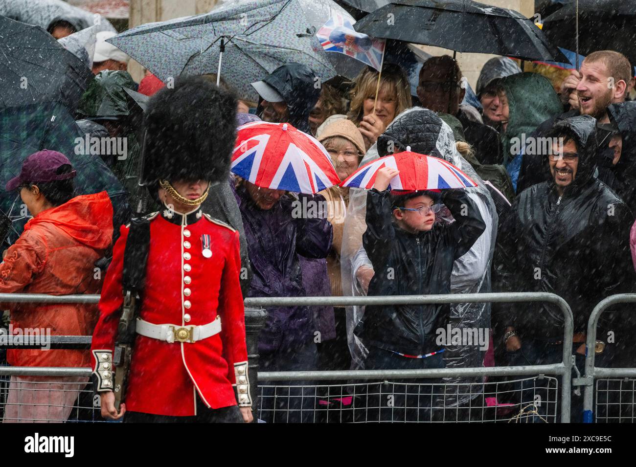 London, Großbritannien. Juni 2024. Starke Regenfälle und die Regenschirme sind draußen, aber Truppen und Zuschauer stehen schnell auf der Hand - Trooping the Colour, um den offiziellen Geburtstag von König Charles III. Zu feiern. Nummer 9 Kompanie, die irische Garde truppieren ihre Farben. Guy Bell/Alamy Live News Stockfoto