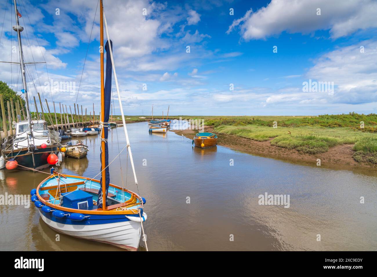 Farbenfrohe Boote auf dem Fluss Glaven in Blakeney, North Norfolk, Großbritannien Stockfoto