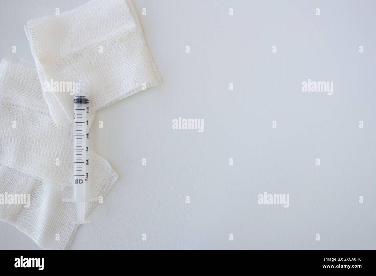 Krankenhausgaze und leere Spritze auf horizontalem Hintergrund mit Kopierraum. Erste Hilfe, Gesundheit, Pflege, Medizinkonzept Stockfoto