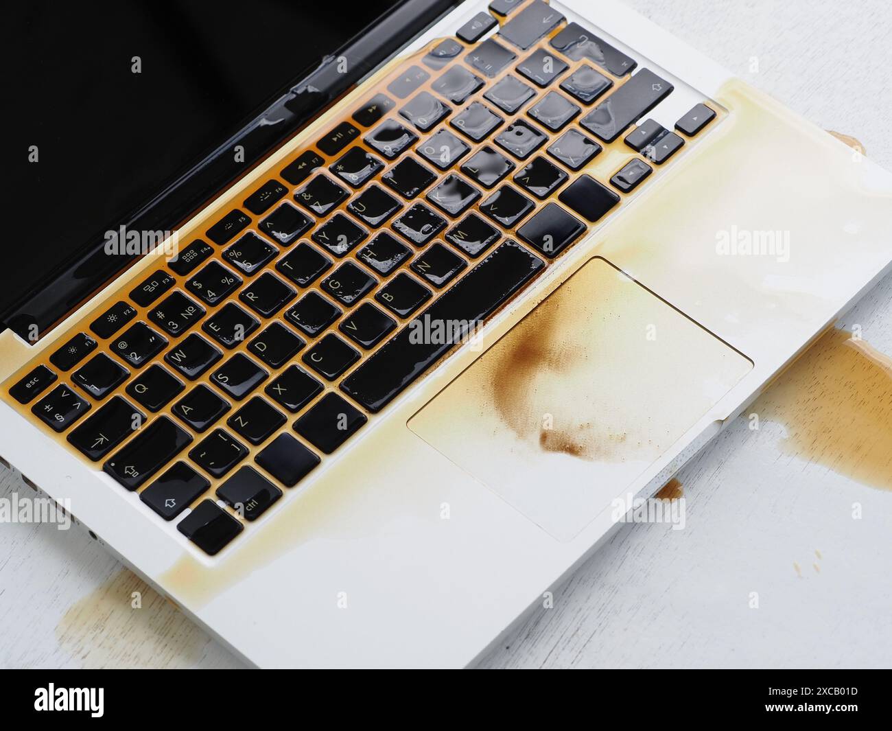 Kaffee ist auf der Tastatur des Laptops verschüttet. Beschädigtes nasses Notebook. Stockfoto