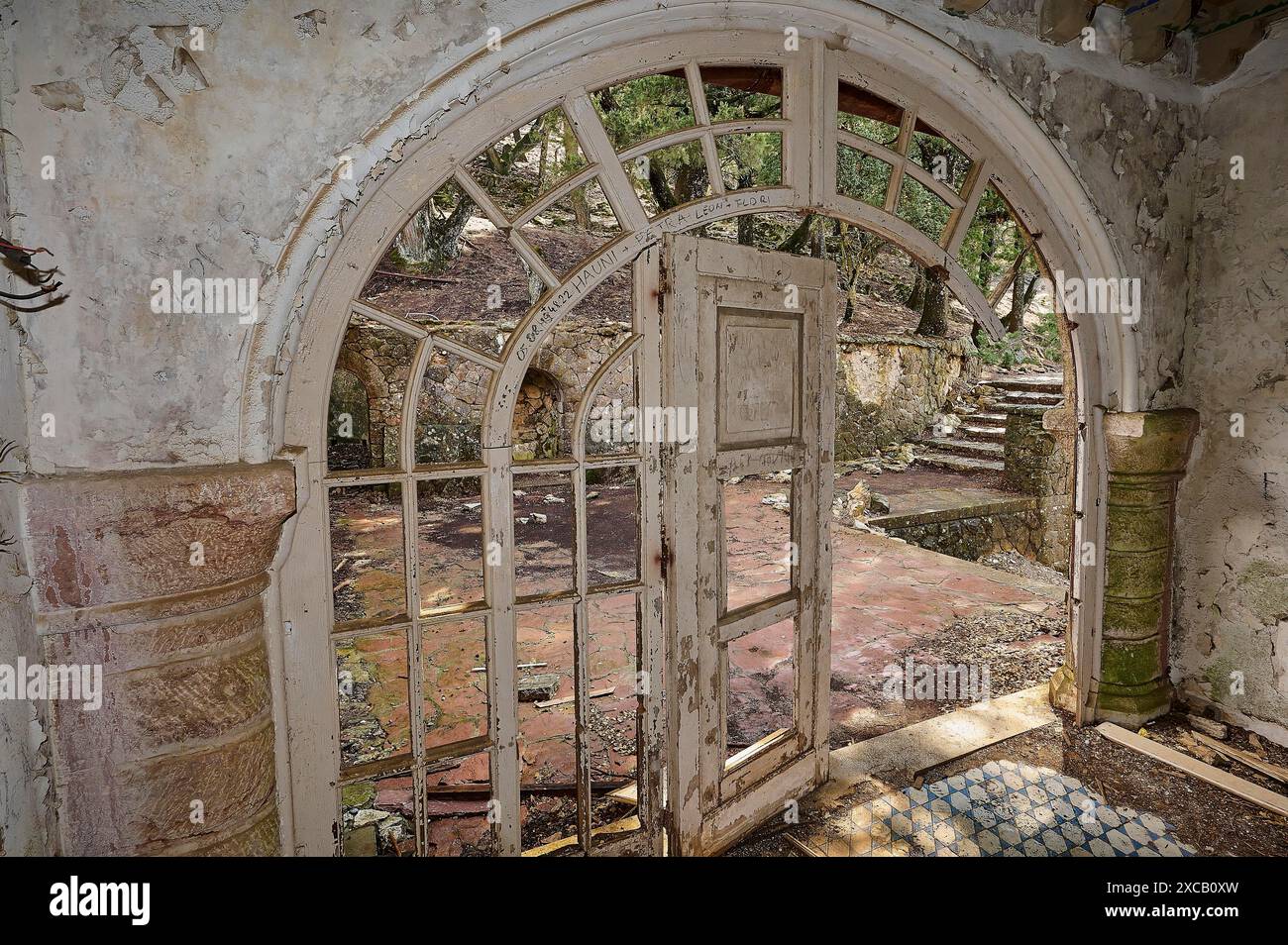 Mussolini Villa, ein verlassenes Gebäude mit einer bogenförmigen Tür, gebrochenen Fensterscheiben und gebrochenen Steintreppen, die ein düsteres und ruinöses Ambiente vermitteln Stockfoto