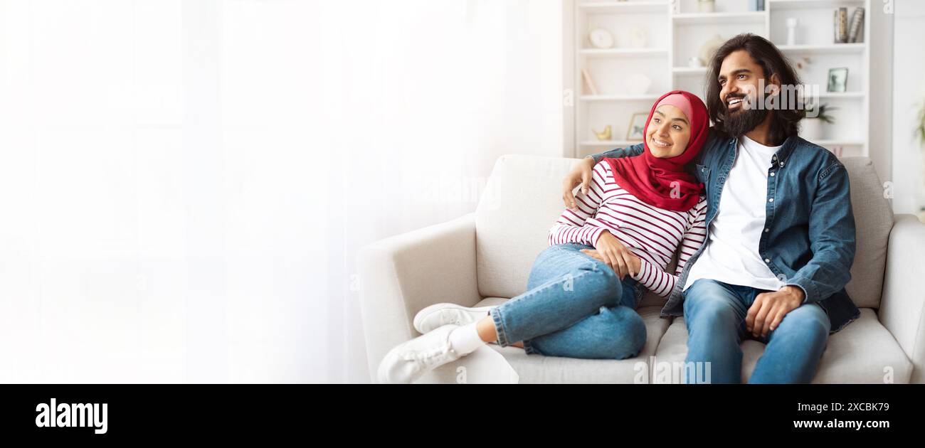 Glückliches Paar, Das Sich Auf Dem Weißen Sofa In Ihrem Wohnzimmer Entspannt Stockfoto