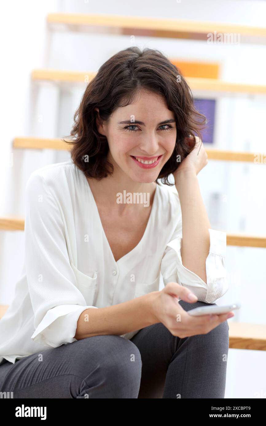 Frau sitzt auf der Treppe und mit Smartphone Stockfoto