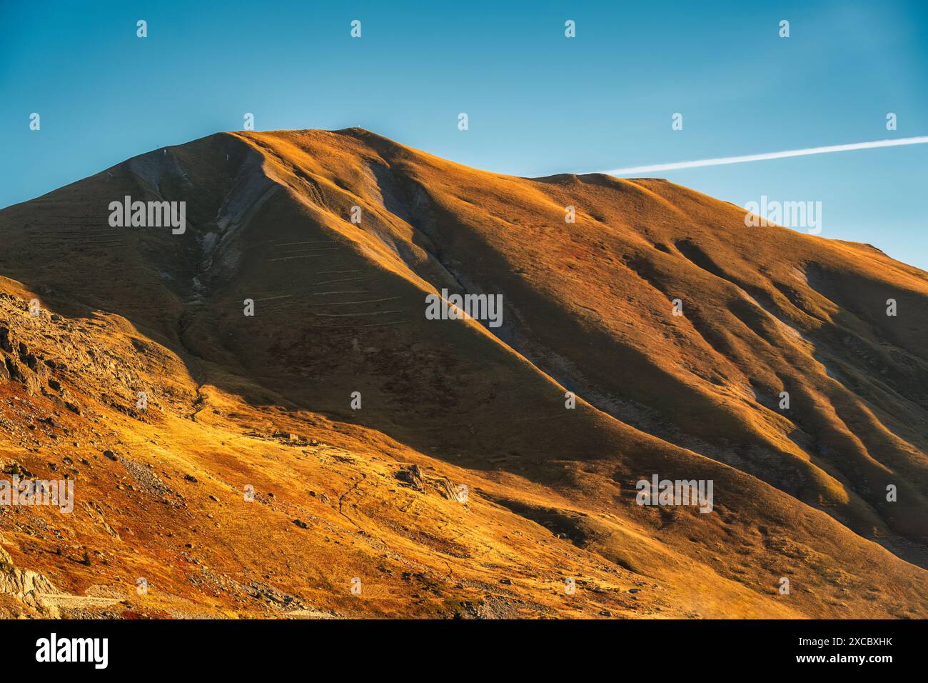 Felsiger Berg bedeckt mit braunem Gras und Sonnenlicht strahlen in der ländlichen Szene der französischen Alpen Stockfoto