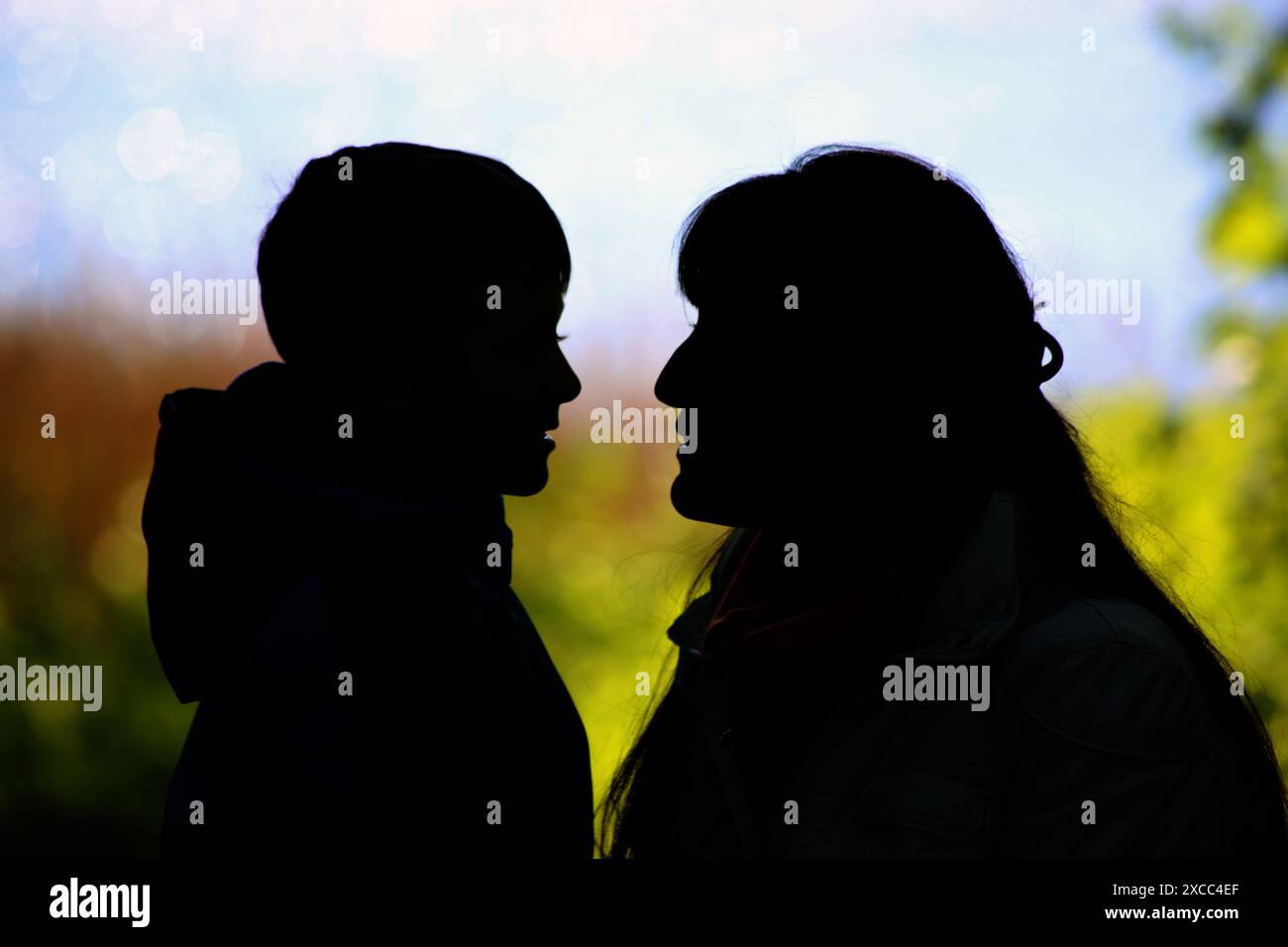 Die Silhouette einer Frau und eines Kindes vor grünem Hintergrund Stockfoto