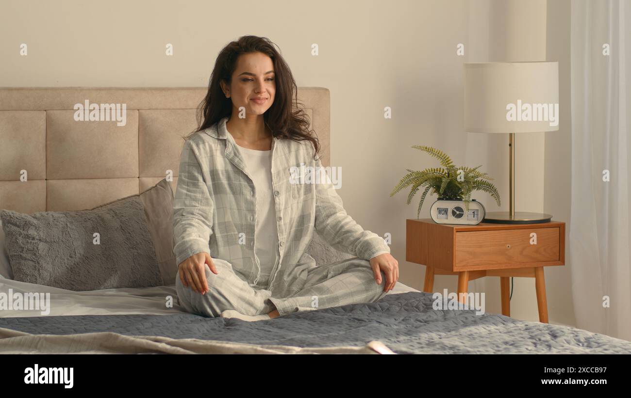 Glückliche kaukasische Frau Bett Schlafzimmer Wohnkomfort Meditieren Vergnügen weibliche Zufriedenheit Stretch Mädchen Erholung früh morgens entspannen Wohlbefinden wach schläfrig Stockfoto