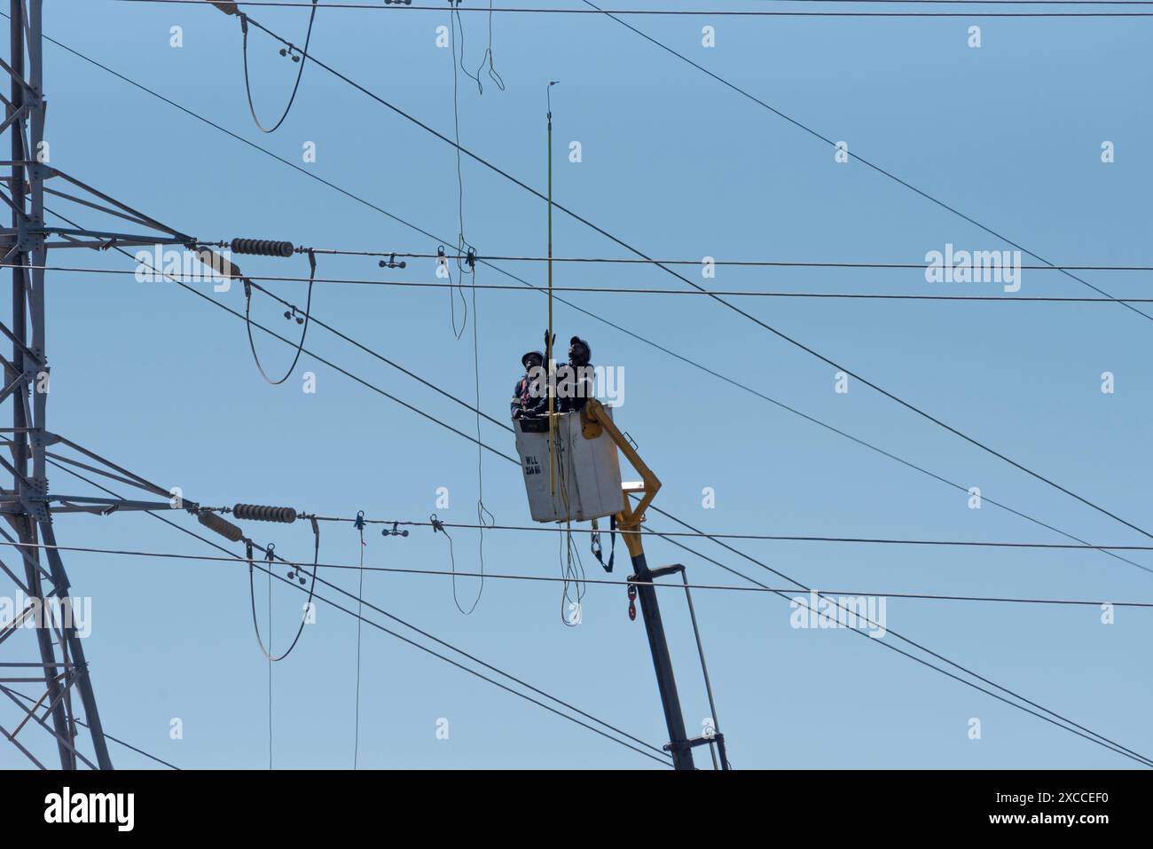 Hopefield, Westkap, Südafrika. 16. 04. 2024. Elektrische Stromleitungen, die die Elektrizität des nationalen Netzes mit Männern versorgen, die von einer Kirsche aus arbeiten Stockfoto