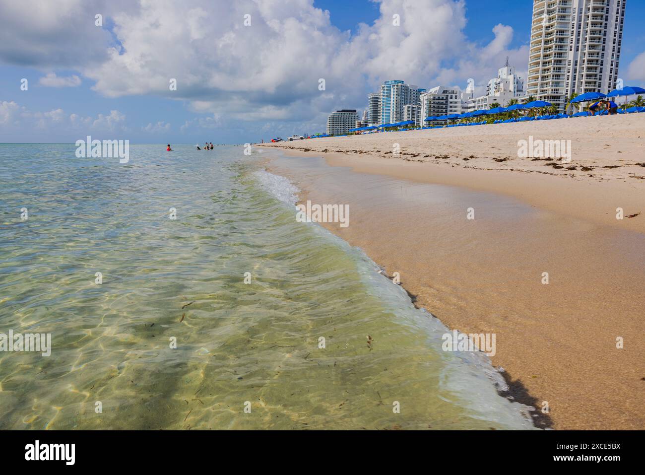 Wolkenkratzer erstrecken sich entlang der Küste von Miami Beach und verschmelzen mit ausgestatteten Sandstränden mit Sonnenschirmen und Liegestühlen. Stockfoto