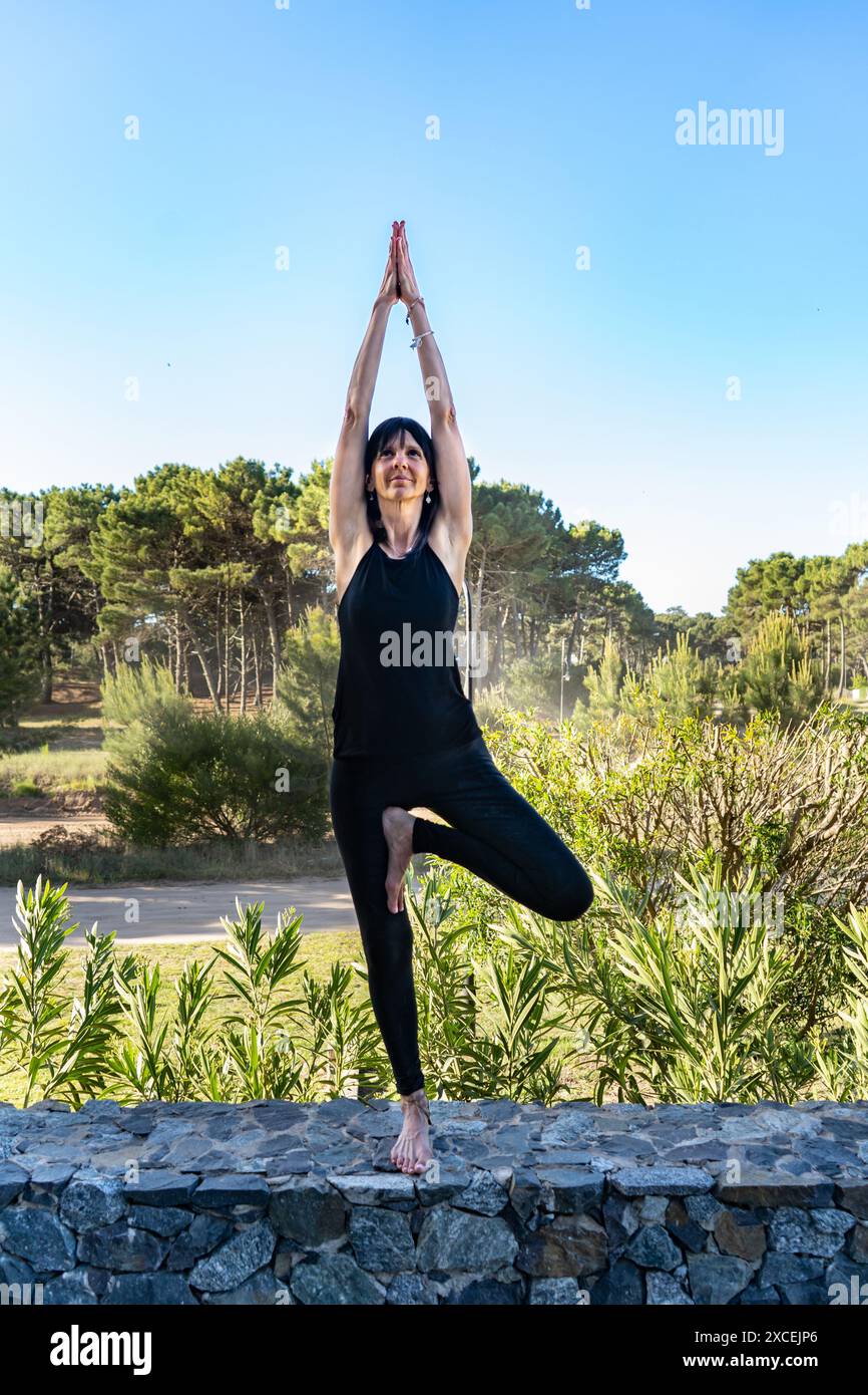 Frau übt Baum mit erhobenen Armen im Freien. Vrikshasana-Pose. Stockfoto