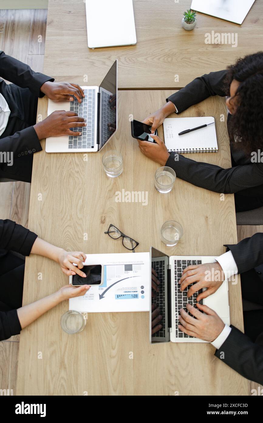 Geschäftskollegen arbeiten gemeinsam an Laptops und Smartphones Stockfoto