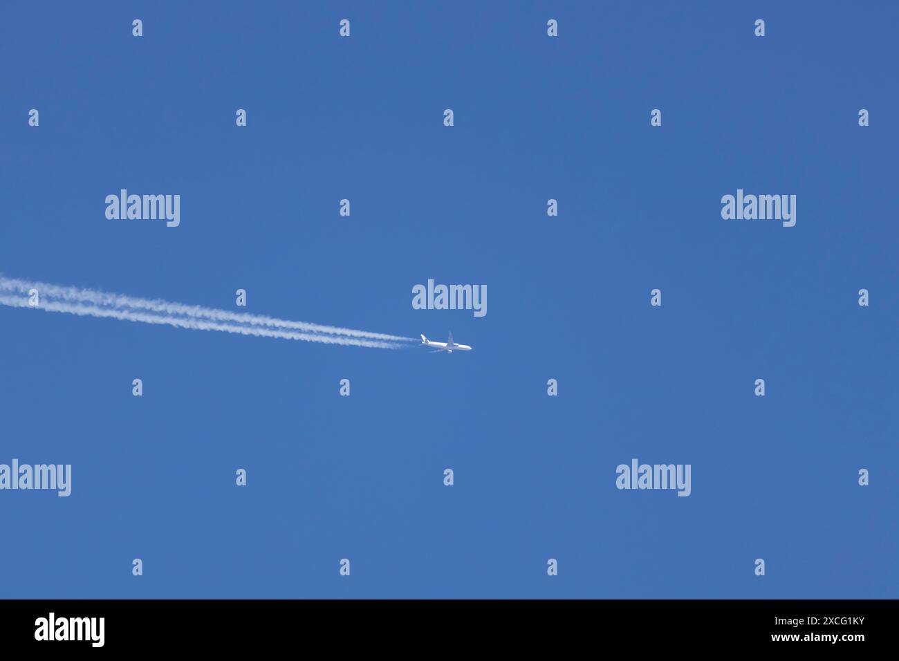 Flugzeug im Flug mit einem Kondensstreifen oder einer Dampfspur über einem blauen Himmel, England, Großbritannien Stockfoto