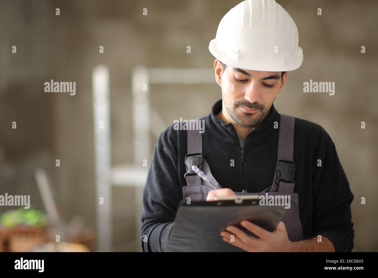 Porträt eines Bauarbeiters, der sich Notizen auf die Zwischenablage in einem Haus macht Stockfoto