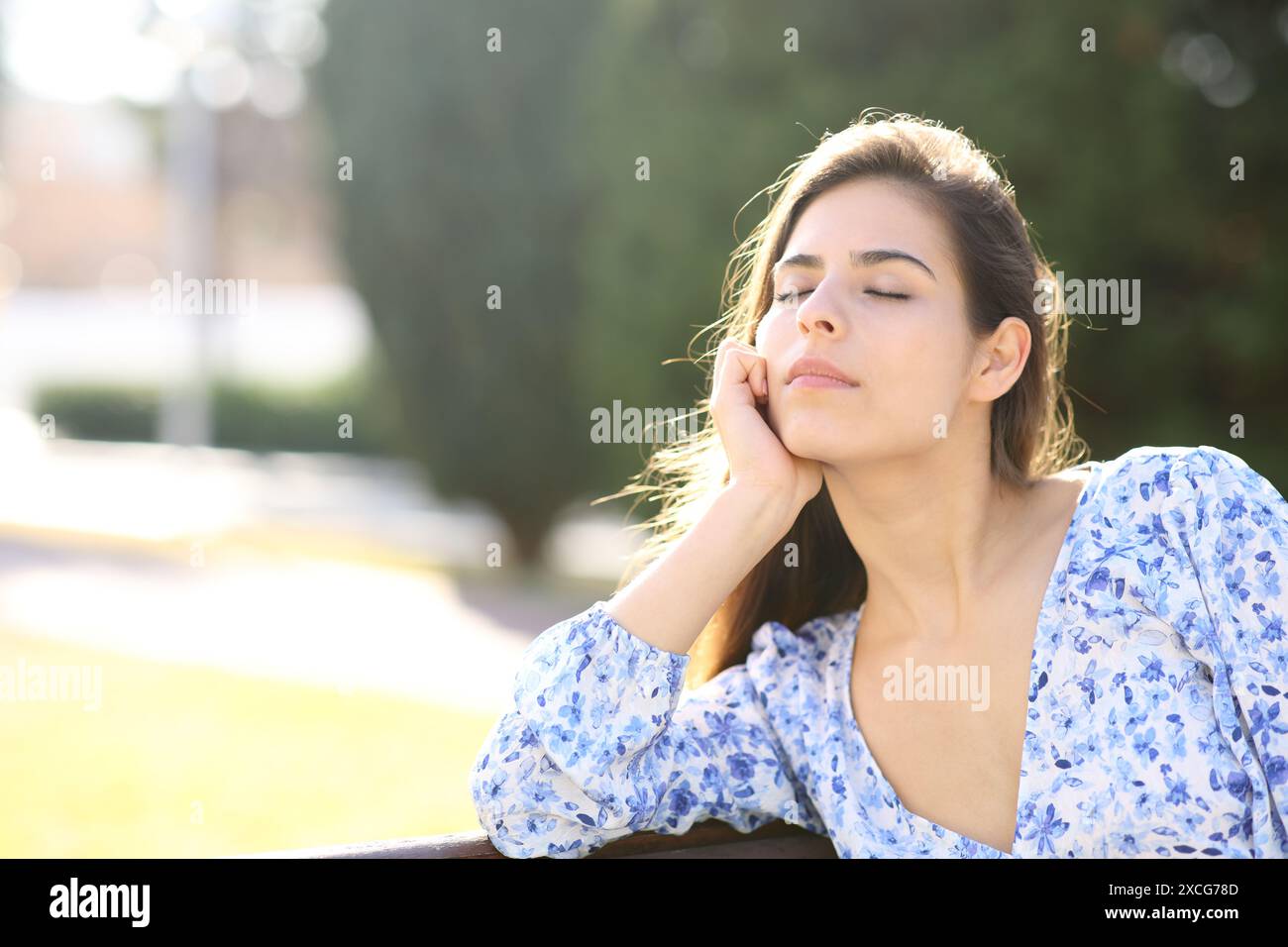 Eine Frau, die allein auf einer Bank im Park sitzt Stockfoto