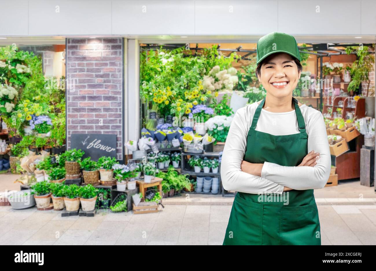 Asiatische Verkäufer tragen grüne Schürze und grüne Kappe, die auf dem Markt lächelnd sind Stockfoto