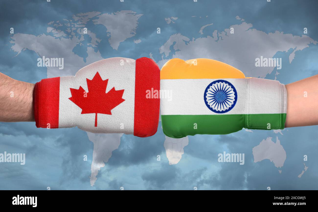 Politischer Konflikt. Männer in Boxhandschuhen mit Flaggen von Kanada und Indien kämpfen gegen die Weltkarte, Nahaufnahme Stockfoto