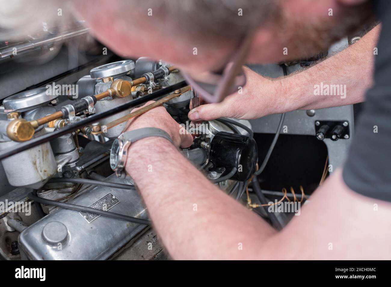 Mechaniker für Rennwagen, der mit einer Fühlerlehre an den elektrischen Punkten im Verteilerkappe arbeitet und diese justiert. Stockfoto