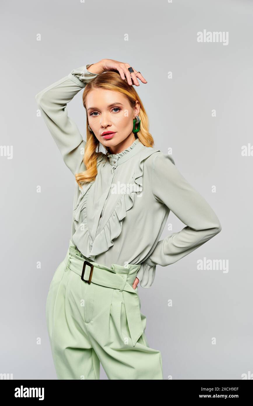 Frau mit grüner Bluse und Hose, die für ein Porträt posiert. Stockfoto