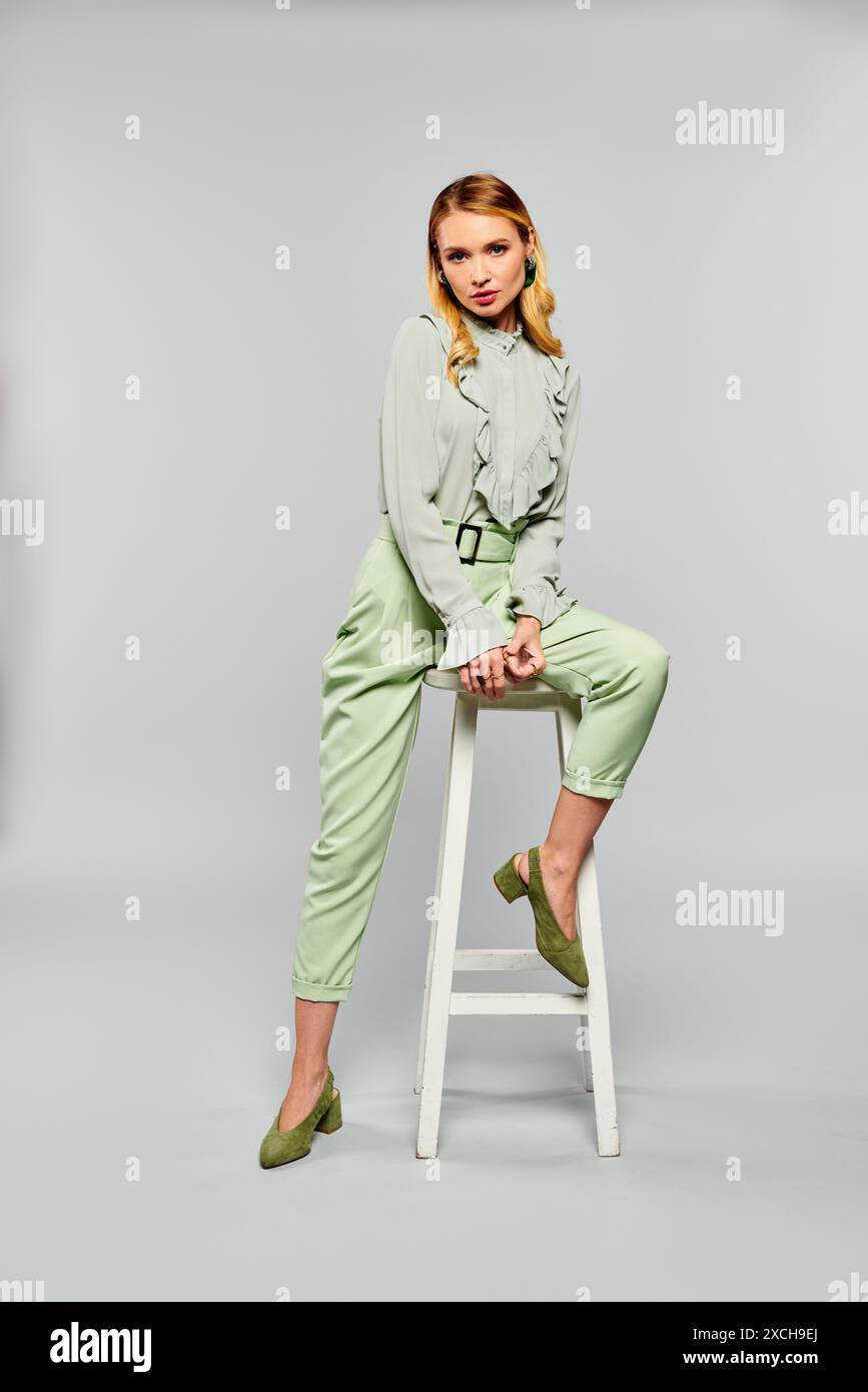 Eine Frau mit grünen Hosen, die auf einem Hocker sitzt. Stockfoto