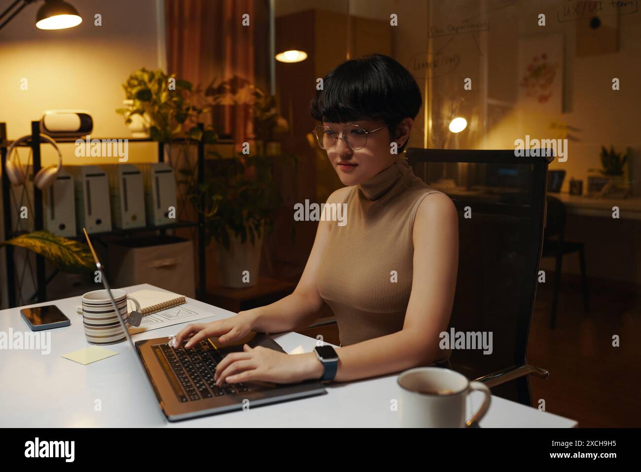 Junger Marketingmanager, der nachts im dunklen Büro am Laptop arbeitet Stockfoto