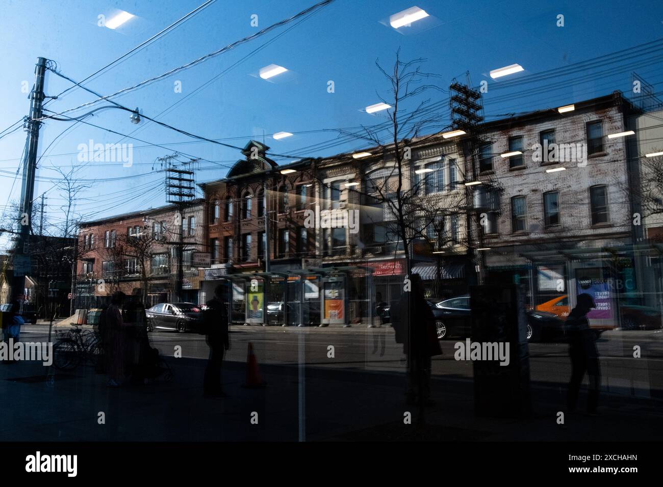 Reflexion einer Straßenszene mit kleinen Wohngebäuden und Silhouetten von Passanten im Kensington Market District von Toronto, Kanadas Öko Stockfoto