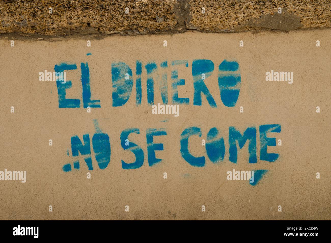 Spanischer Graffitti in einer Wand mit der Aufschrift „man kann kein Geld essen“ Stockfoto
