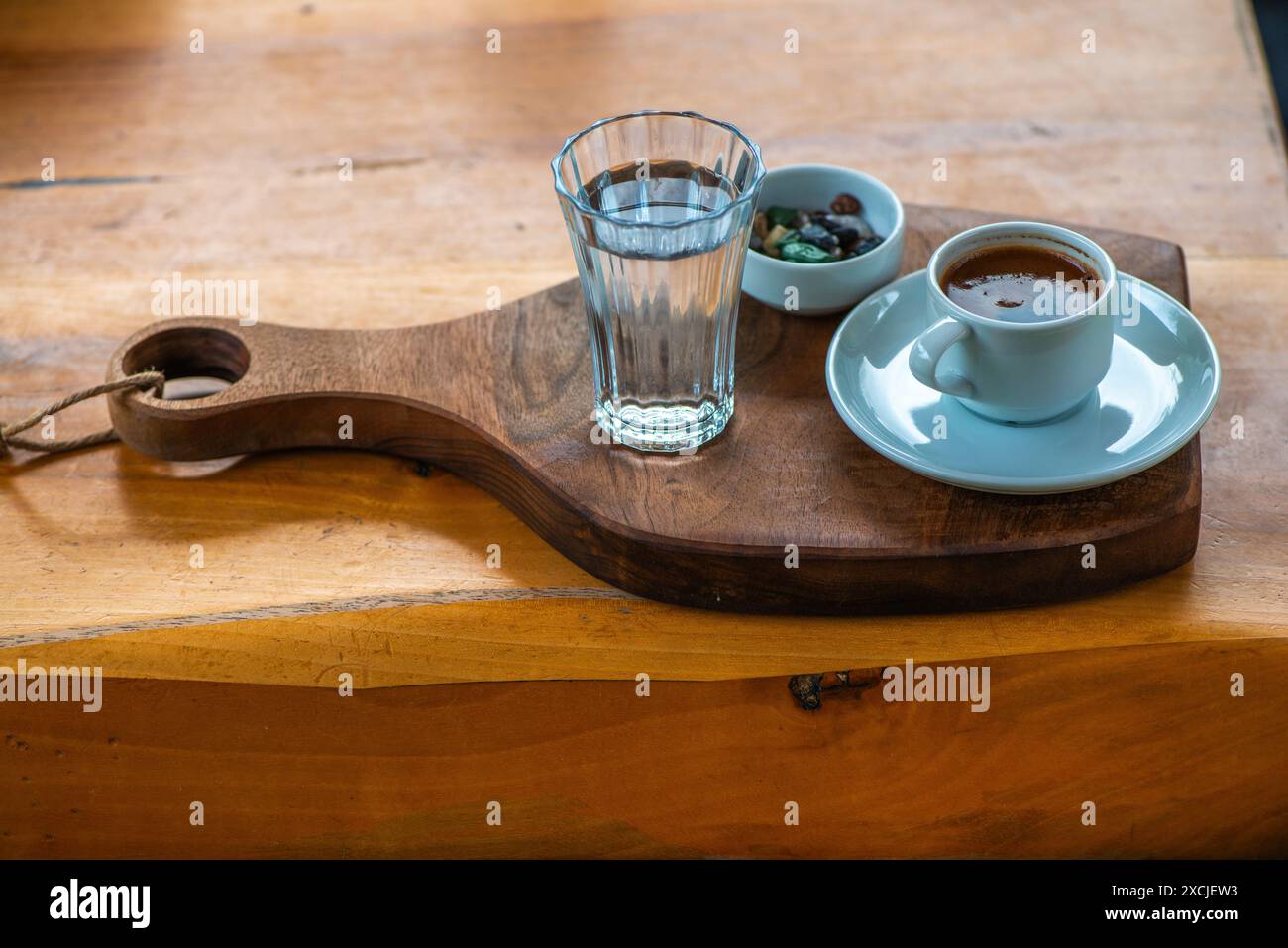 Türkische Kaffeepräsentation mit Kieselschokolade und einem Glas Wasser, mit traditioneller, eleganter Einrichtung auf dem Tisch. Stockfoto