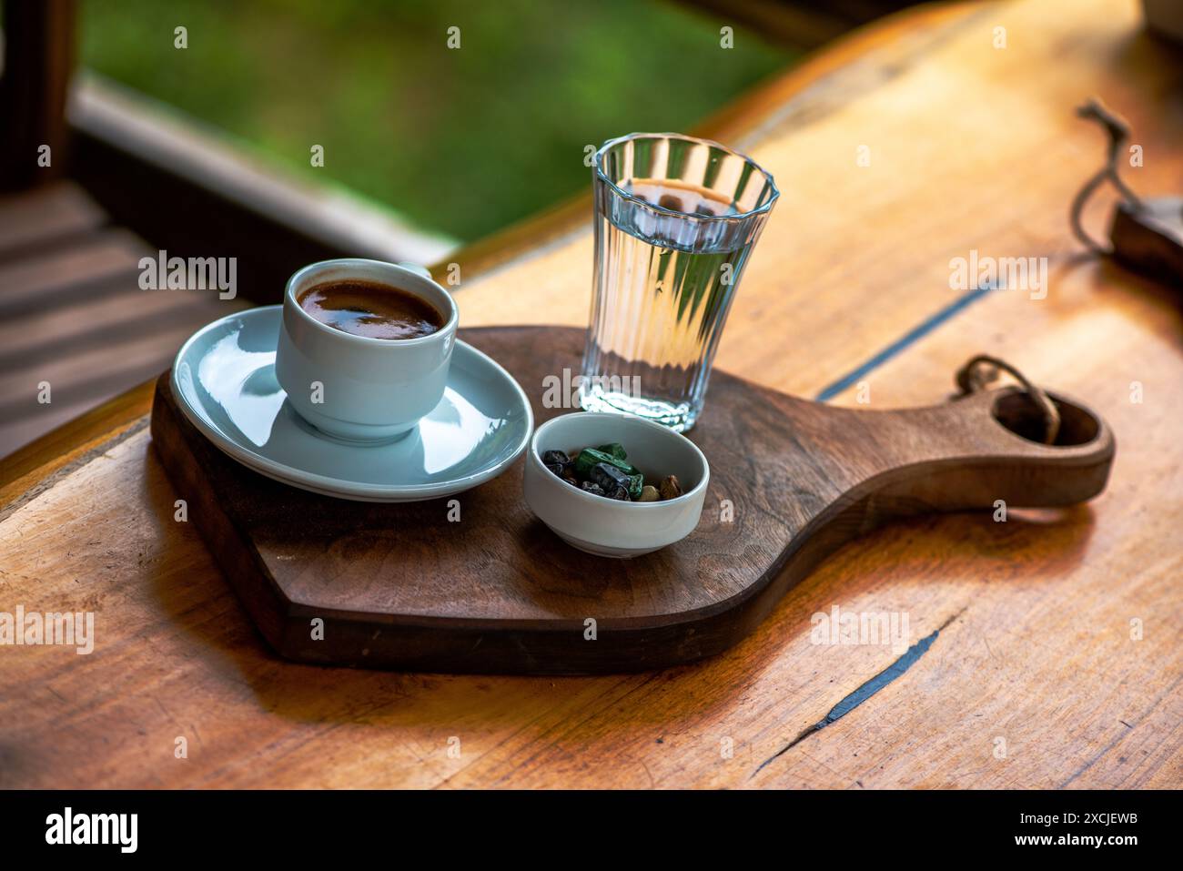 Türkische Kaffeepräsentation mit Kieselschokolade und einem Glas Wasser, mit traditioneller, eleganter Einrichtung auf dem Tisch. Stockfoto