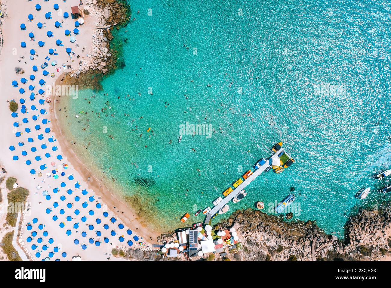 Aus der Vogelperspektive auf einen Strand von Konnos voller Menschen, die in einem türkisfarbenen Wasser schwimmen. Bezirk Famagusta, Zypern Stockfoto