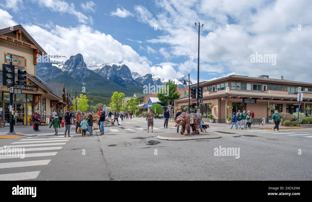 Canmore, Alberta, Kanada – 16. Juni 2024: Die Menschen genießen die Main Street in der Innenstadt mit Mount Rundle im Hintergrund Stockfoto