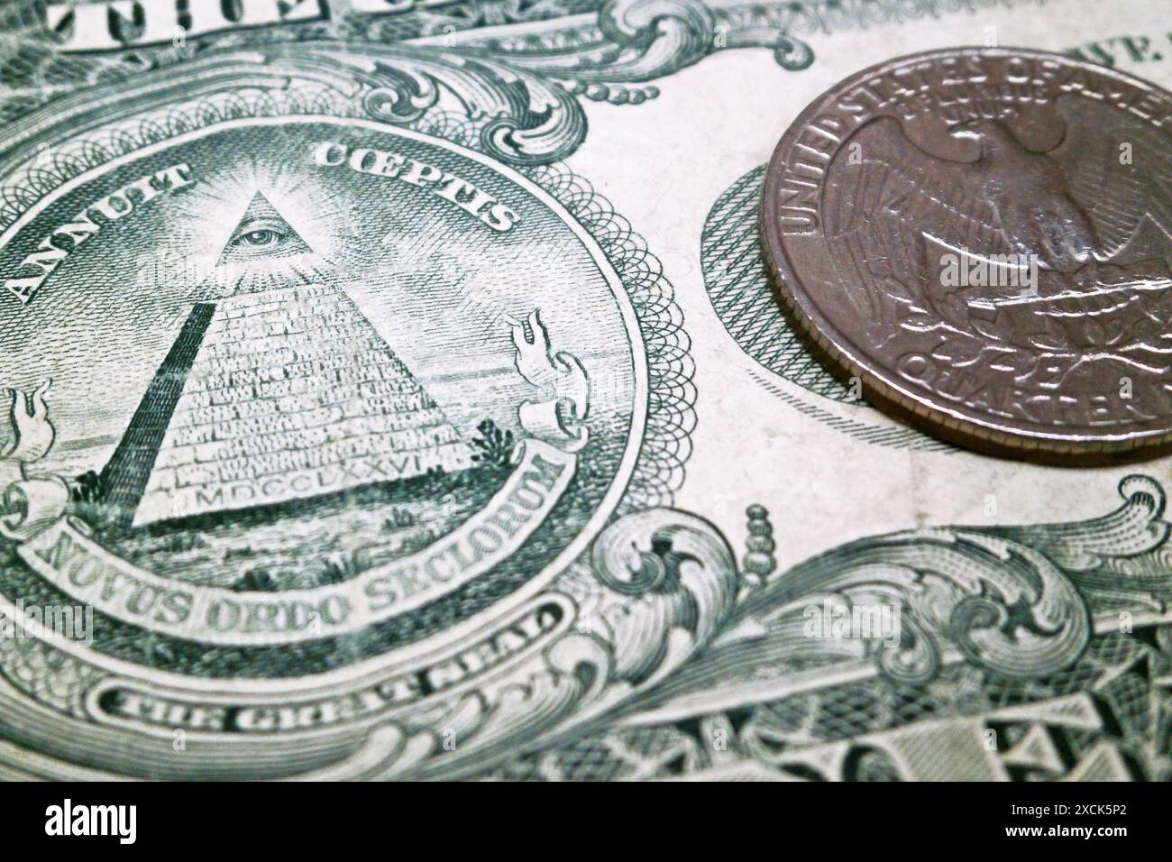 Nahaufnahme eines 1-Dollar-Scheins mit dem Fokus auf das Auge der Vorsehung und auf den Adler mit 25-Cent-Münze. Stockfoto