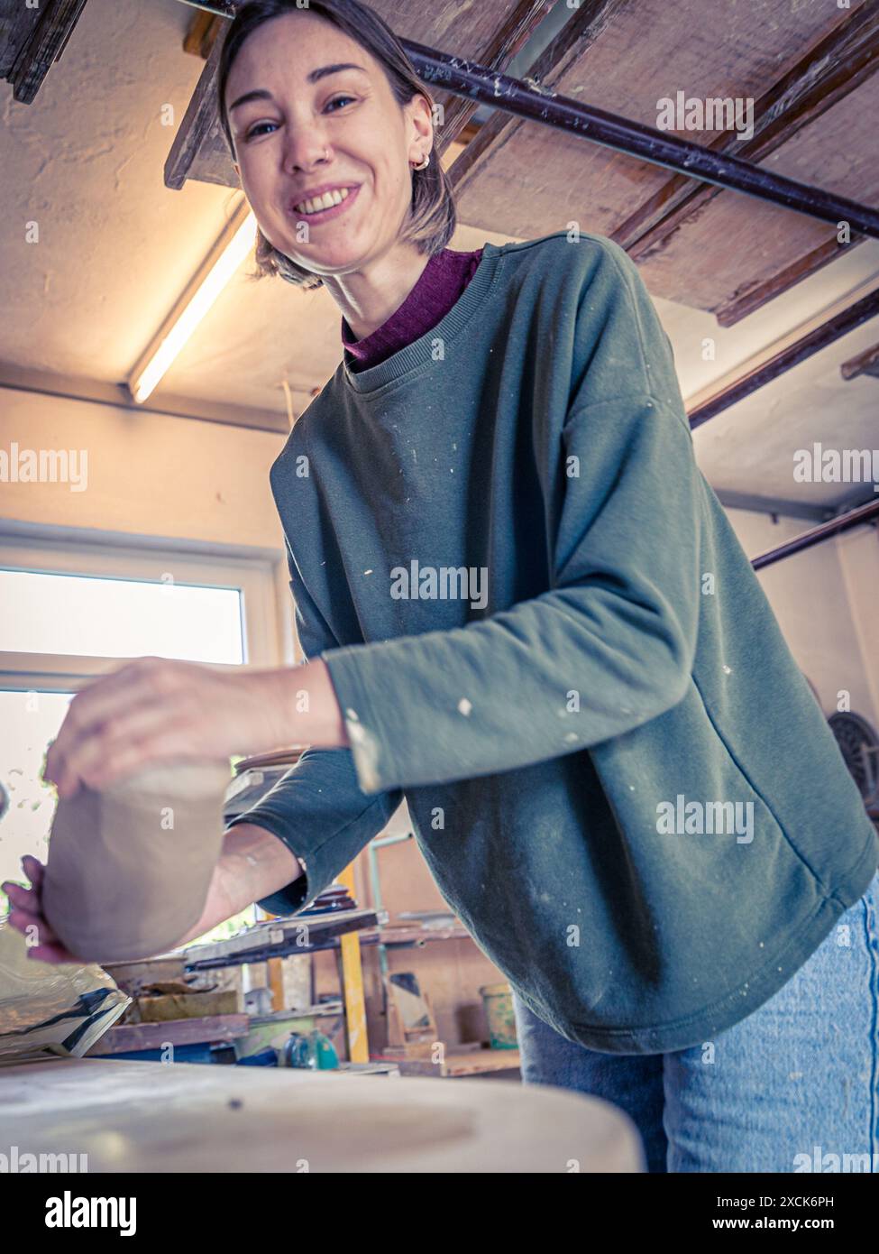 Kappeln, Deutschland. Juni 2024. Anastasia Krasikova, eine Lehrerin bei der Stock-Töpferei, hat ein Stück Ton gewogen und zu einer rauen Form geknetet. Der Ton wird später auf einem Töpferrad verarbeitet. Die Stock-Töpferei befindet sich nun in der dritten Generation in Kappeln an der Schlei. Sie wurde 1947 von der Großmutter des heutigen Eigentümers gegründet. Derzeit arbeiten hier sieben Personen, darunter drei Auszubildende. Vermerk: Frank Hammerschmidt/dpa/Alamy Live News Stockfoto