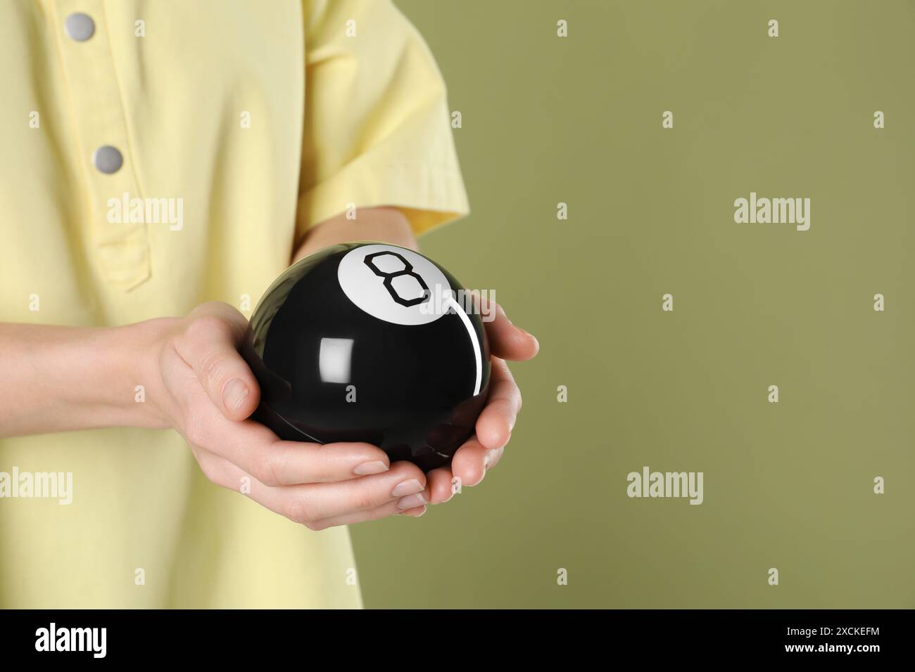 Mann mit magischem Acht-Ball auf olivfarbenem Hintergrund, Nahaufnahme. Leerzeichen für Text Stockfoto