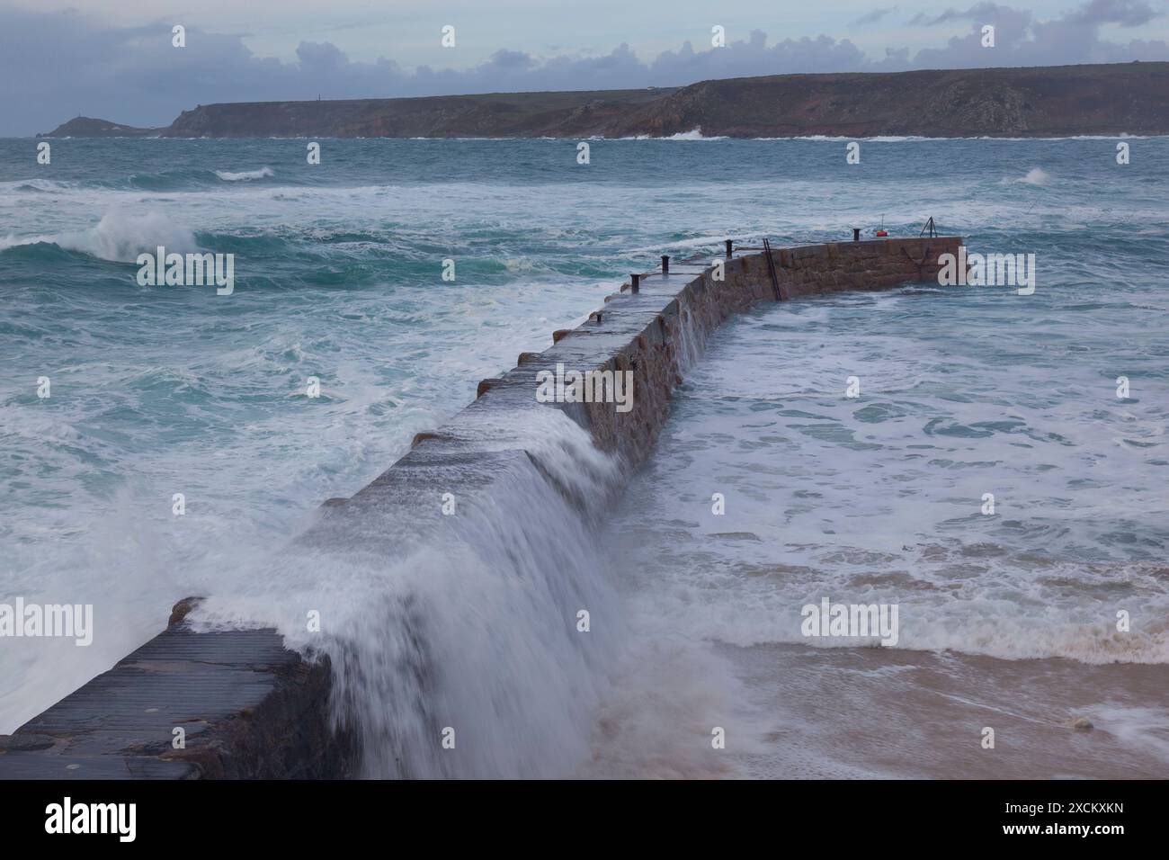 Die Welle stürzt über Sennen Coves Jetty, Cornwall Stockfoto