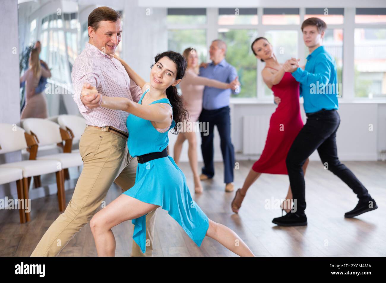Junge Brünette in Blau engagierte sich im Tango mit Partner im Tanzstudio Stockfoto