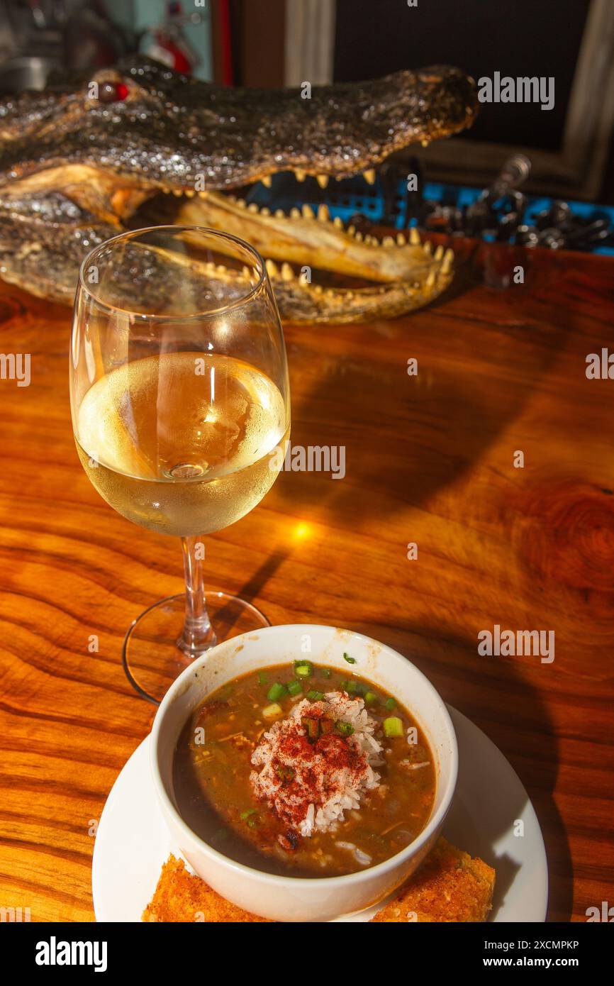 New Orleans Gumbo mit Wein und einem Alligatorkopf im Hintergrund Stockfoto