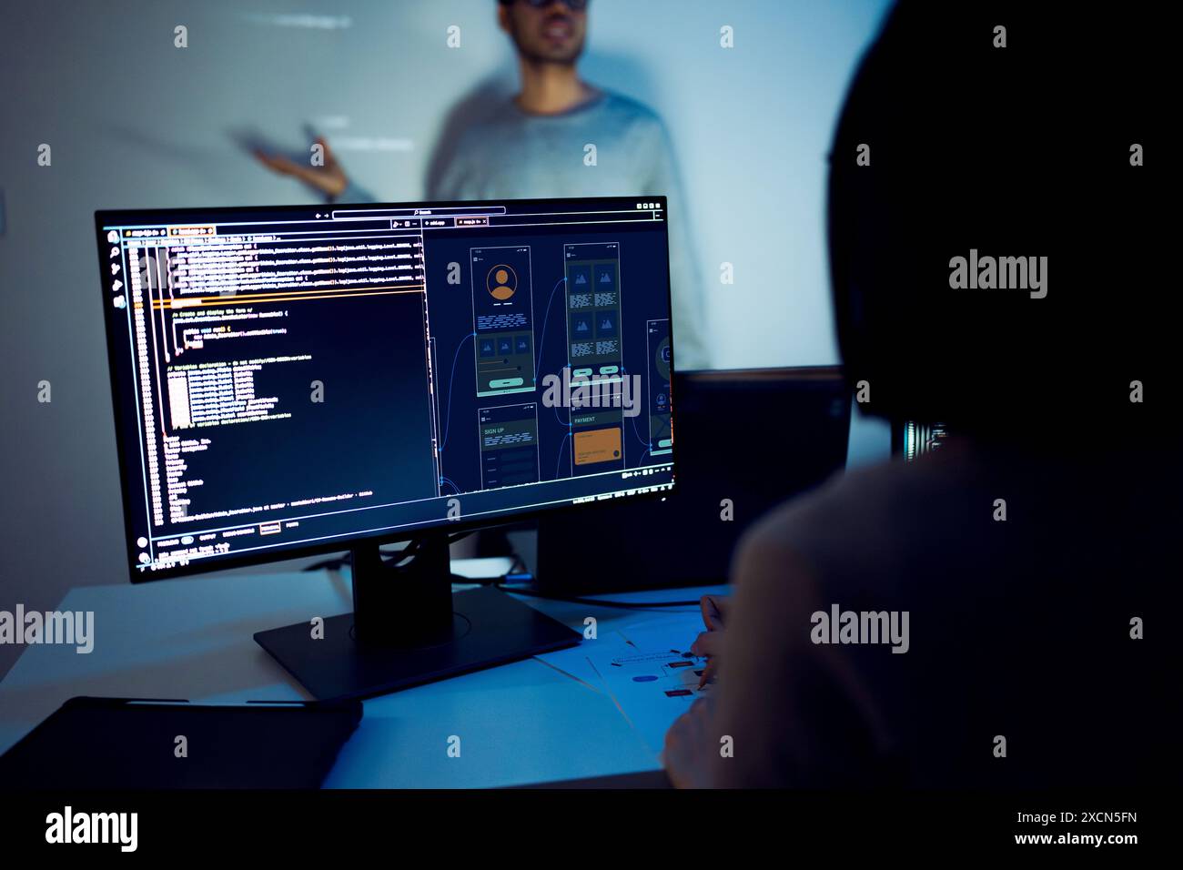 asiatische Entwickler leiten die Sitzung zur Codeüberprüfung und zeigen auf Code, der an der Wand projiziert wird, zusammen mit Kollegen, Teamarbeit und Wissensaustausch über Software Stockfoto