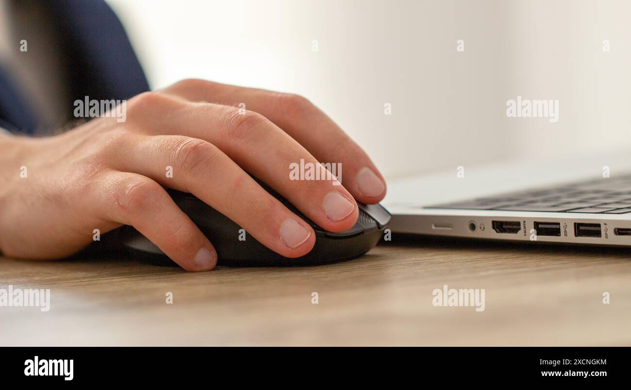 Männliche Hand auf einer Computermaus, Arbeitsplatz mit Laptop Stockfoto