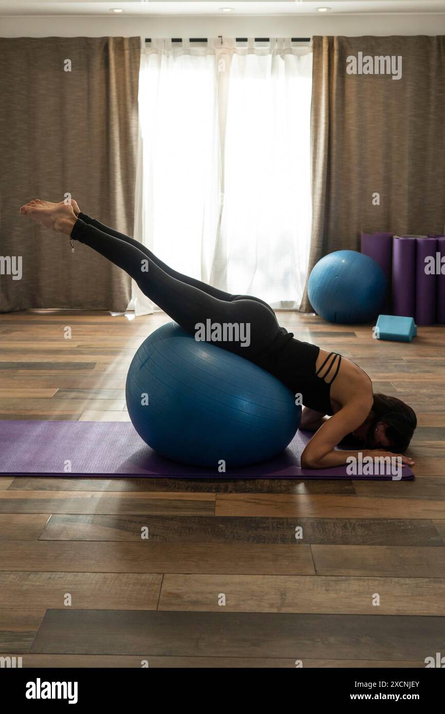 Ein professioneller Yogatrainer führt Übungen mit Fitnessball durch Stockfoto