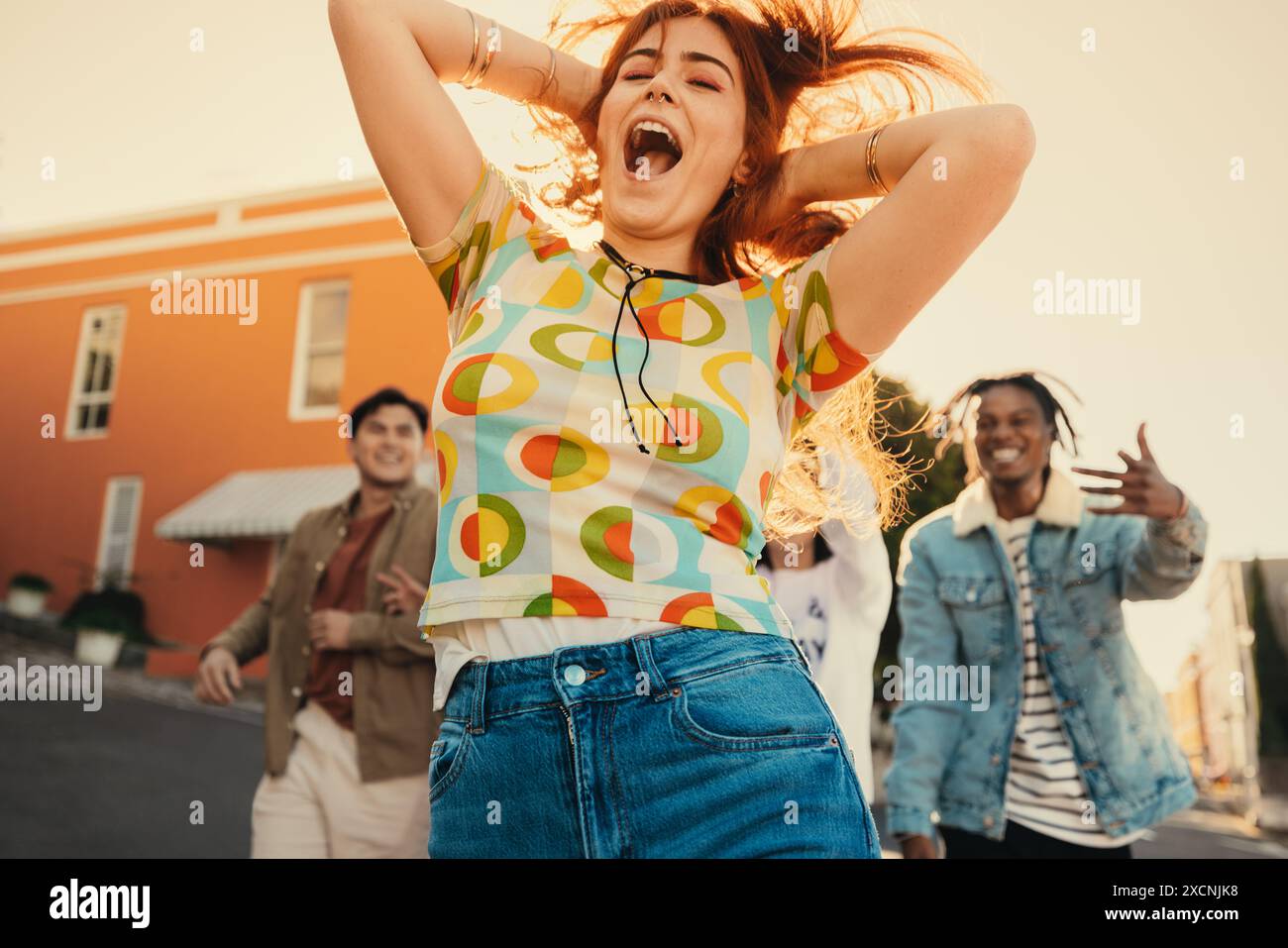 Gen Z Gruppe von Freunden, die Spaß beim Tanzen haben und einen lebendigen Moment für soziale Medien aufnehmen. Frau, die den Tanz draußen anführt. Stockfoto