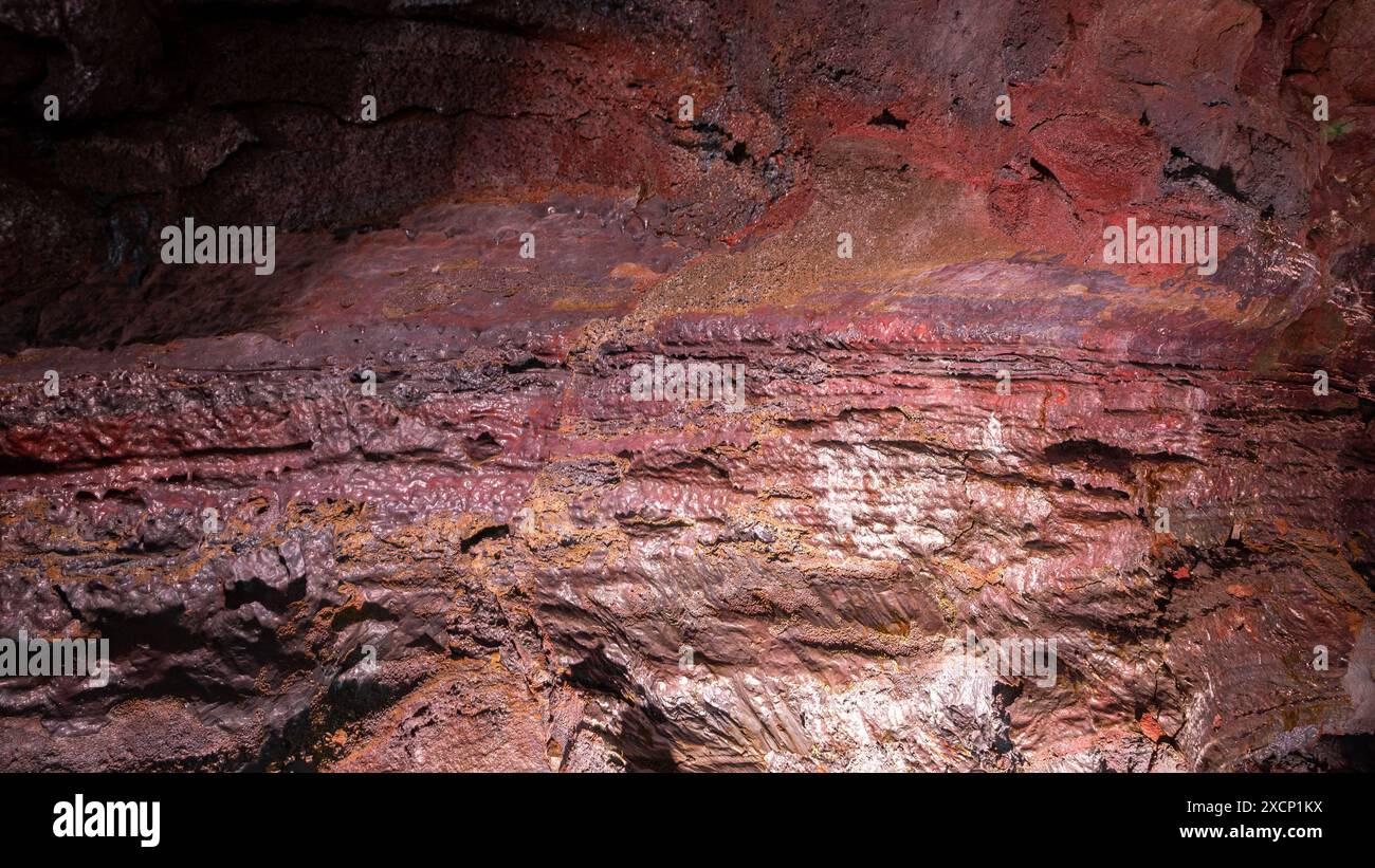 Wand des Lava-Tunnels (Raufarholshellir), Nahansicht der roten und braunen Eisenvulkangesteine, Island. Stockfoto
