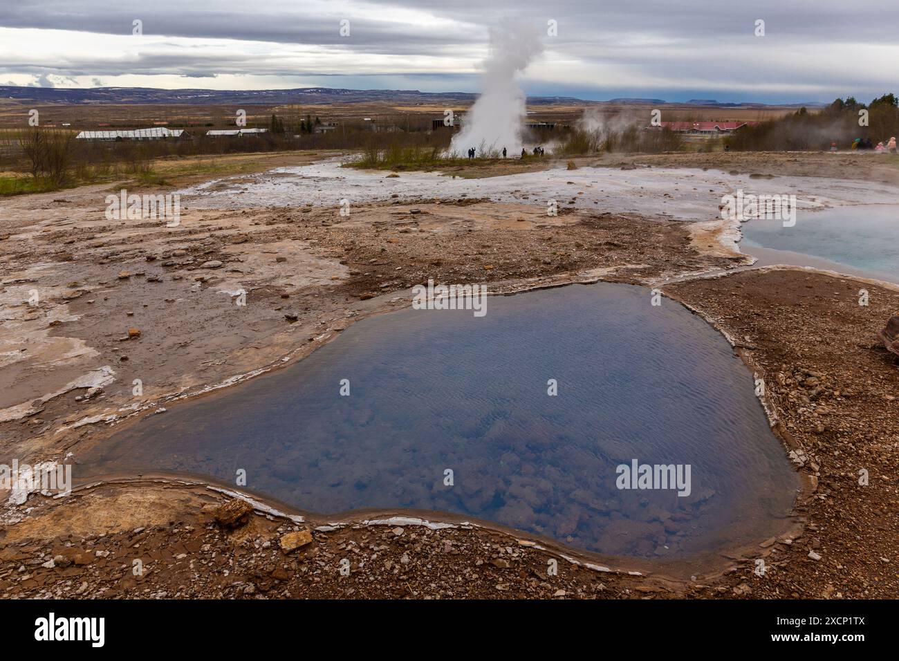 Geysir Geothermie-Landschaft in Island mit heißen Quellen und Pools, Strokkur Geysir, der im Hintergrund ausbricht. Stockfoto