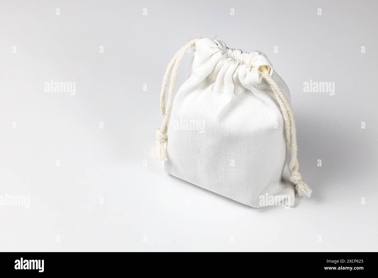 Kleiner Öko-Sack, Calico Canvas-Tasche mit Kordelzug, Modell eines kleinen Öko-Sacks aus natürlichem Baumwollgewebe isoliert auf weißem Hintergrund. Stockfoto