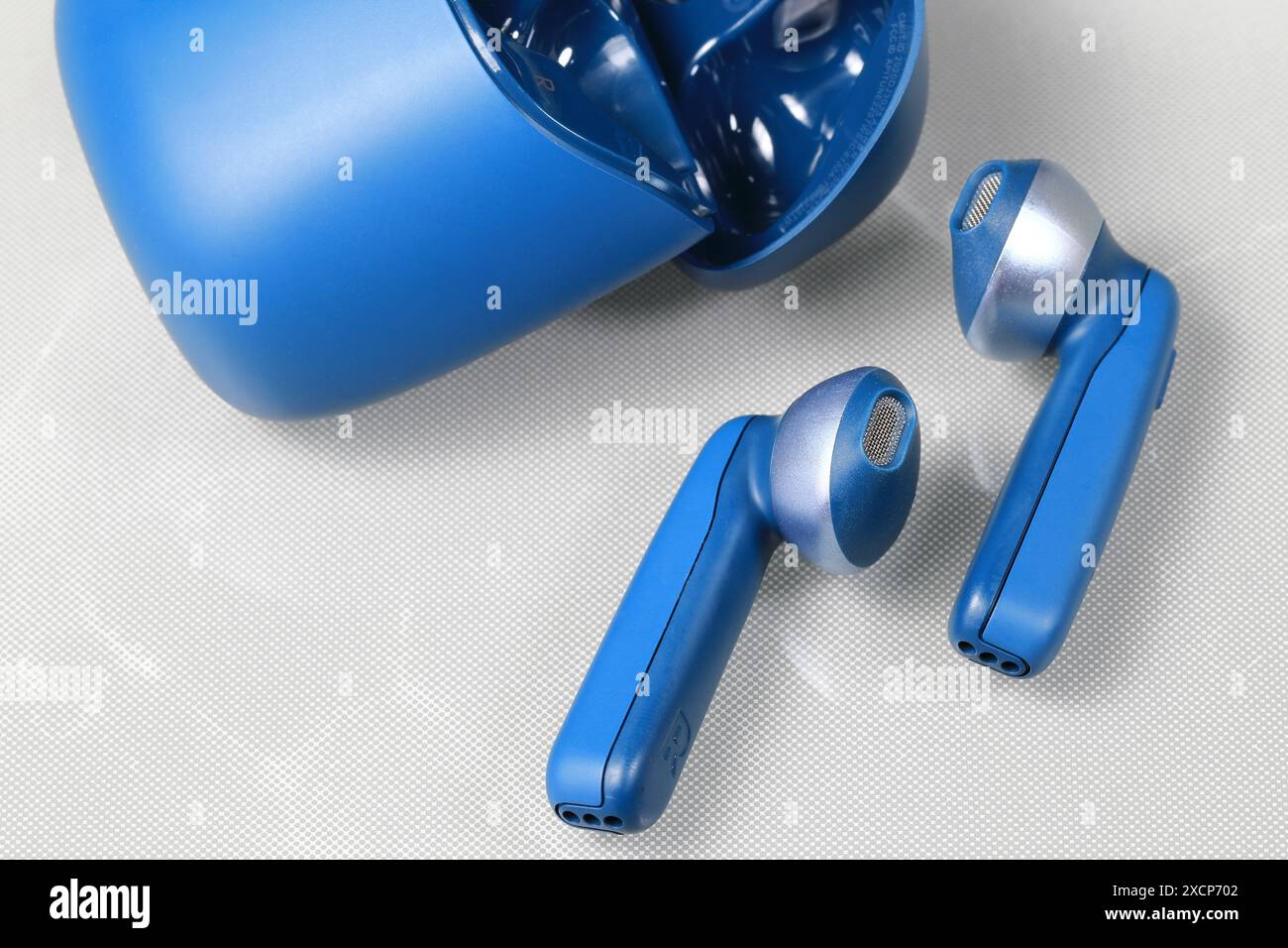 Blauer bluetooth kabelloser Kopfhörer oder Ohrhörer oder Kopfhörer mit Ladetasche auf weißem Hintergrund. Stockfoto